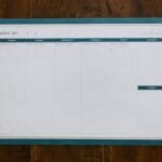 Top view of a blank weekly planner on a wooden surface, perfect for organizing your week.