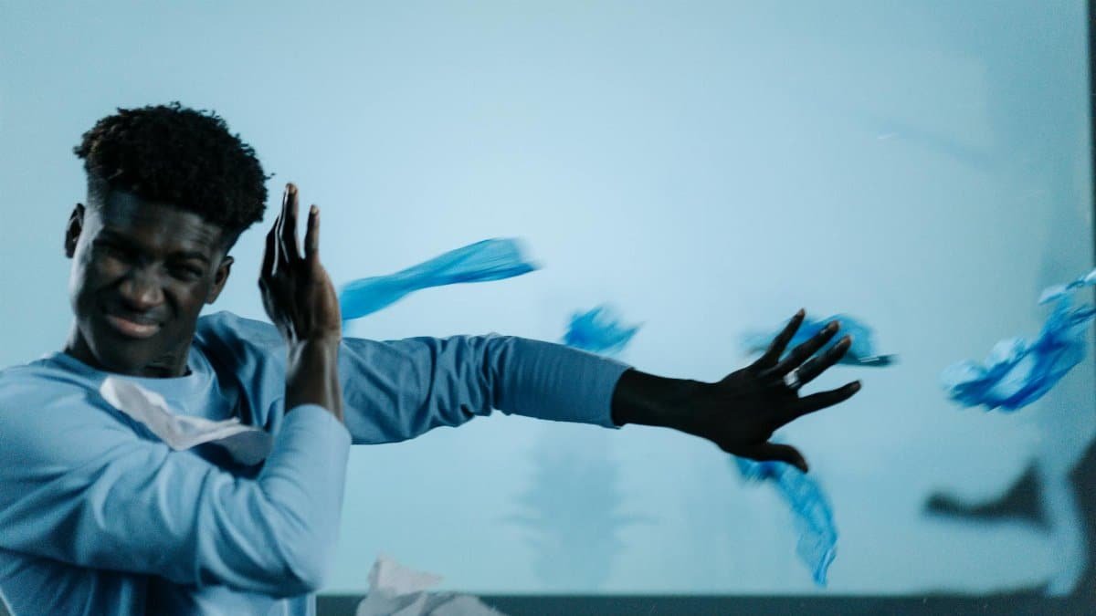 A man shields himself from flying plastic waste indoors.