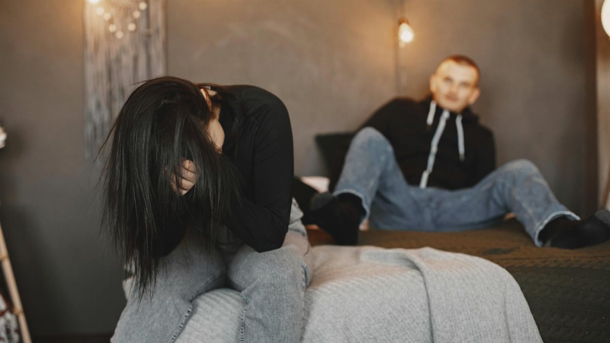 A couple having an intense conversation on a bed, reflecting relationship tension.