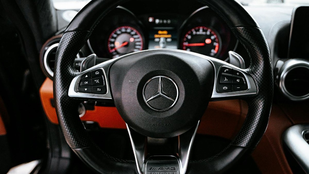 Detailed view of a luxury car steering wheel with control buttons and dashboard.