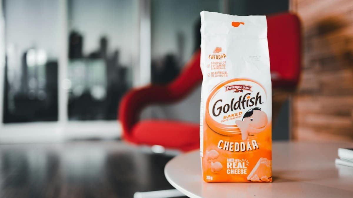 Close-up of Goldfish cheddar crackers pack on a table with red chair backdrop.