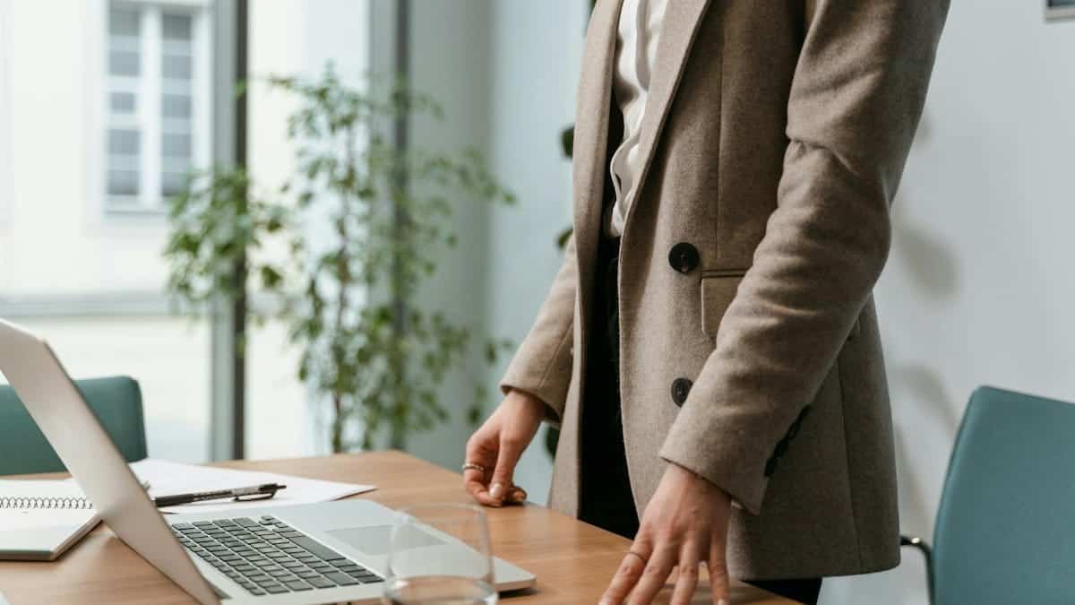 A professional businesswoman in a stylish office environment with a laptop and notes.