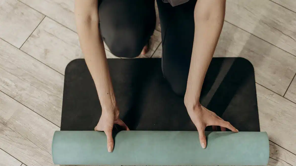 Close-up of individual rolling out a yoga mat on wooden floor, ready for a home workout.