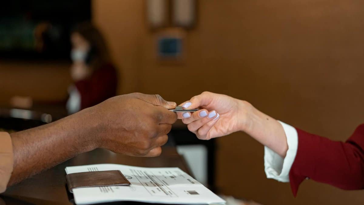 Close-up of a hotel receptionist receiving a credit card from a guest, highlighting a transaction at check-in.