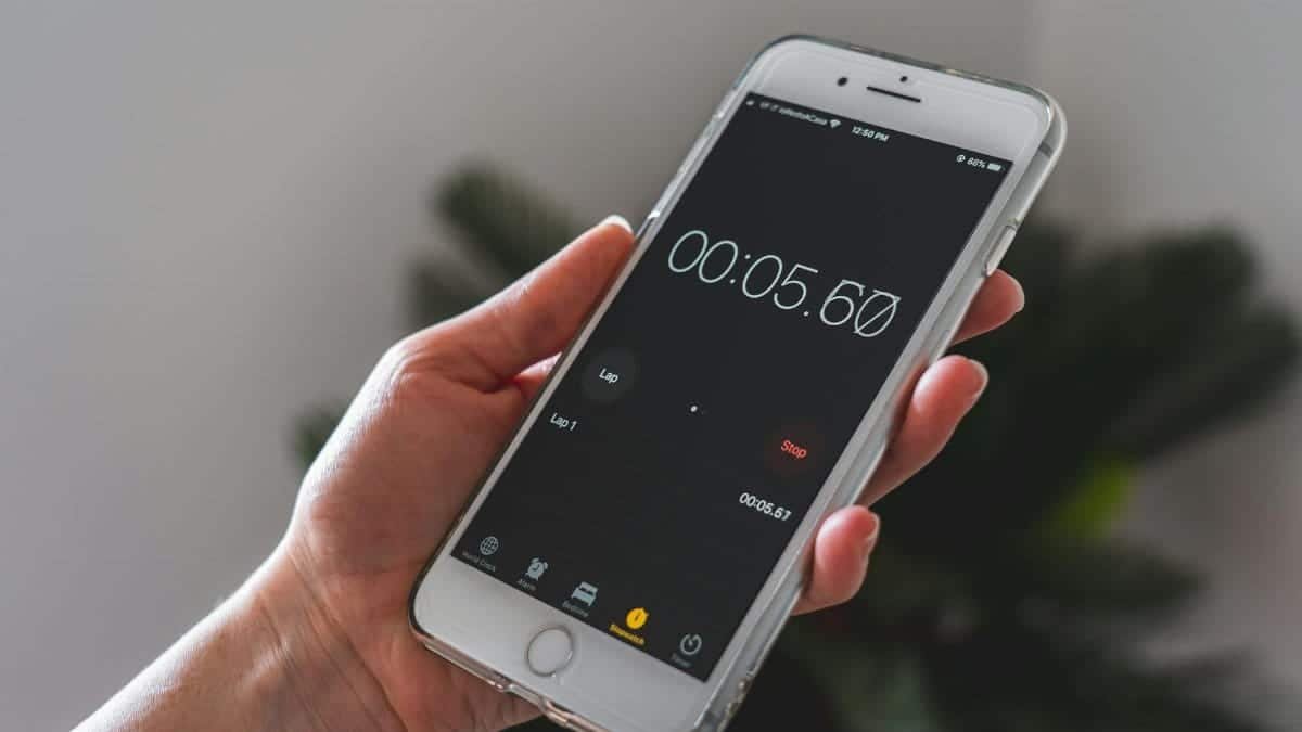 Close-up of a hand holding a smartphone with a stopwatch app running.