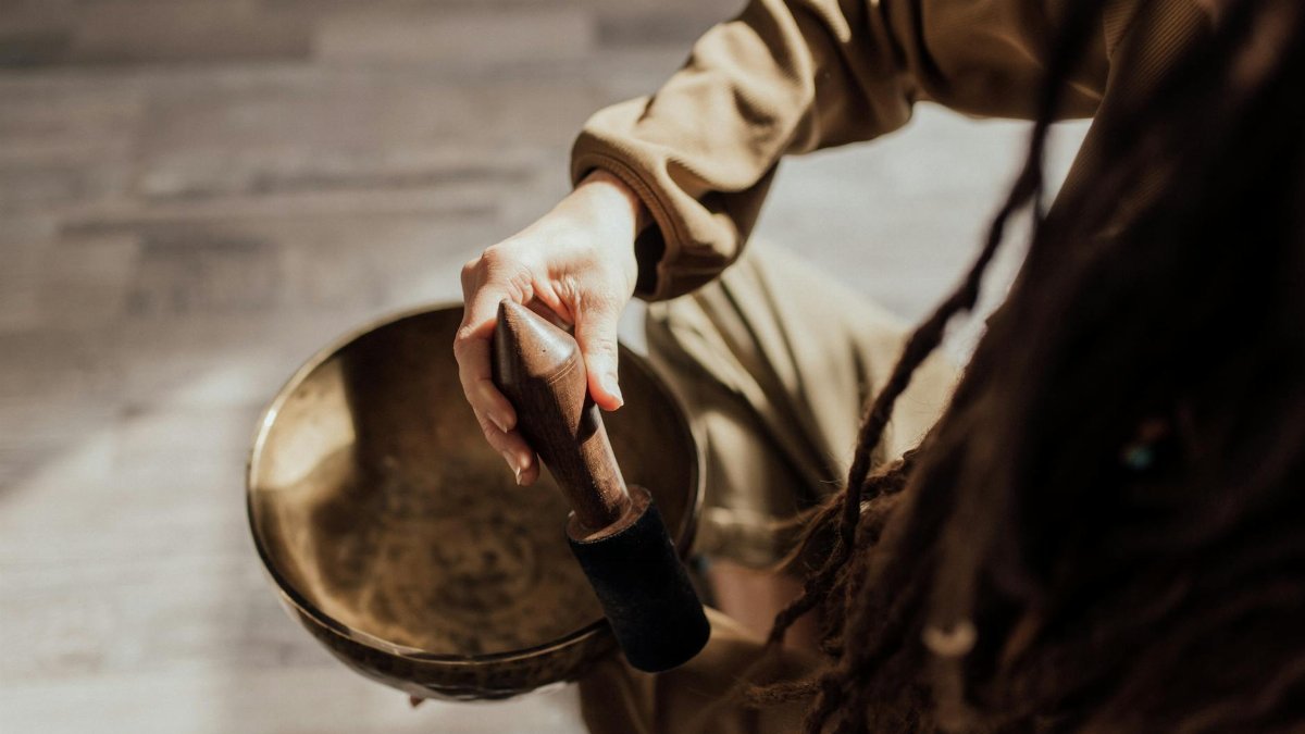 Close-up of a person using a singing bowl, demonstrating meditation sound therapy.