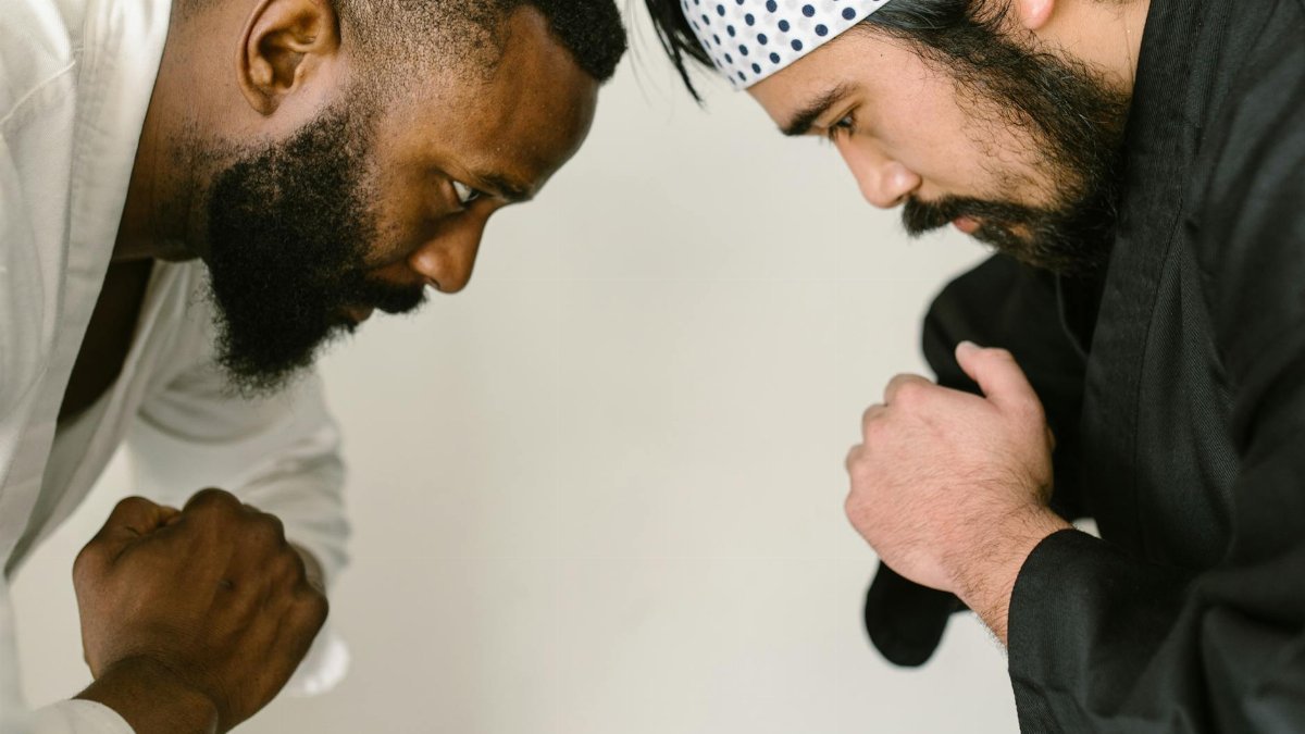 Two martial artists in traditional attire bowing in a moment of respect and focus.