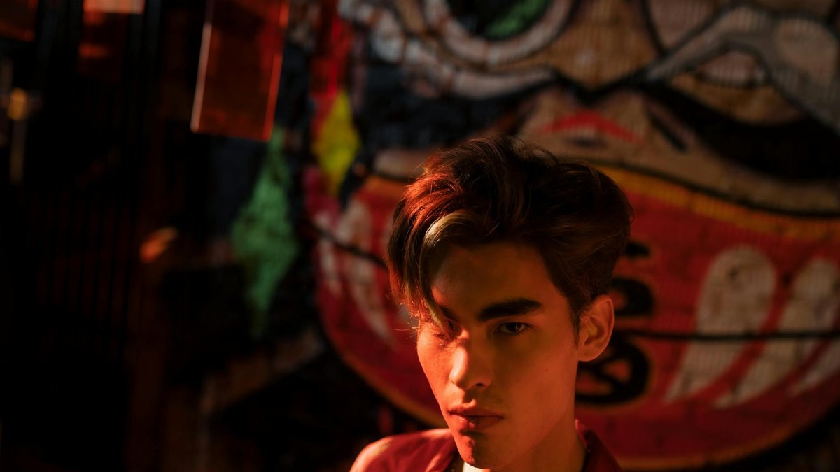Emotive portrait of a man illuminated by dramatic light against vibrant graffiti art.