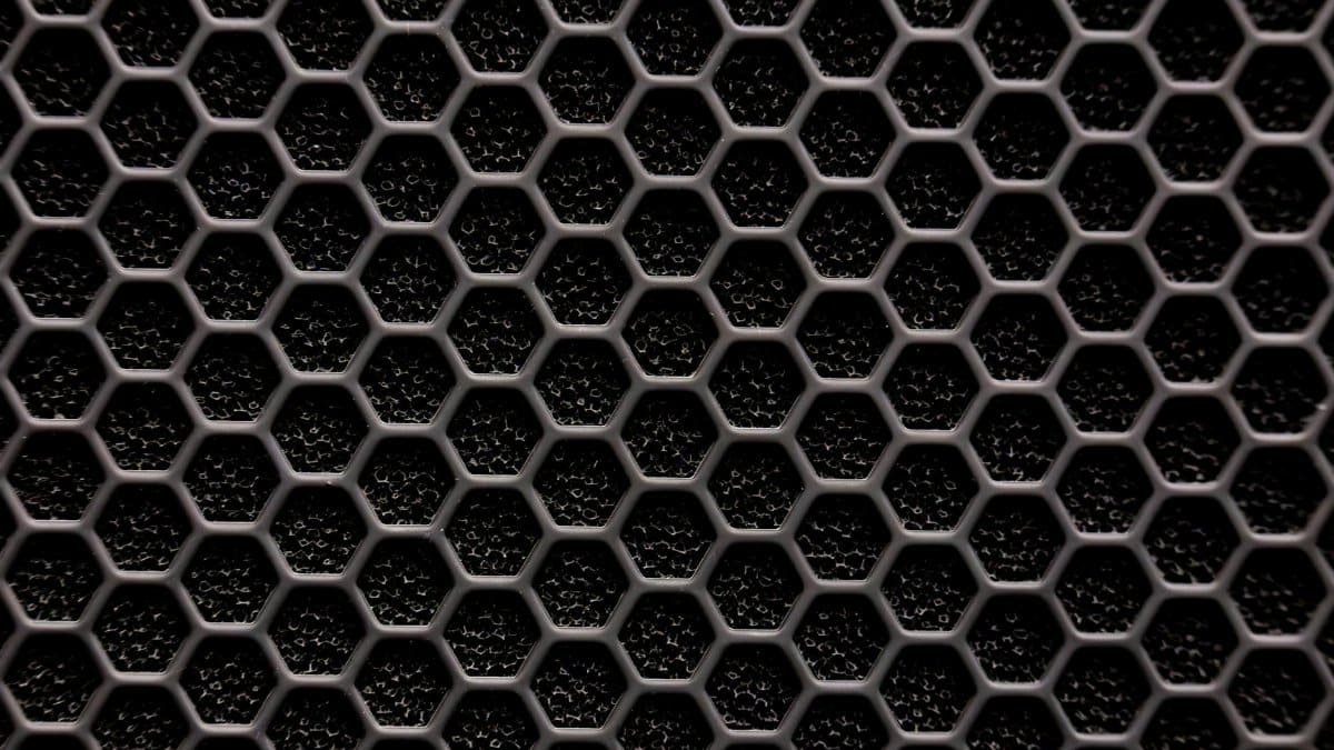 Close-up of a metallic hexagonal grid pattern, resembling a honeycomb structure.