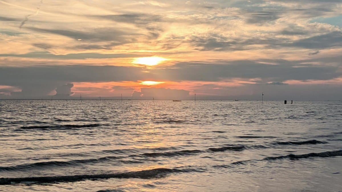 Peaceful ocean sunset with gentle waves and vibrant sky colors, perfect for a tranquil summer evening view.