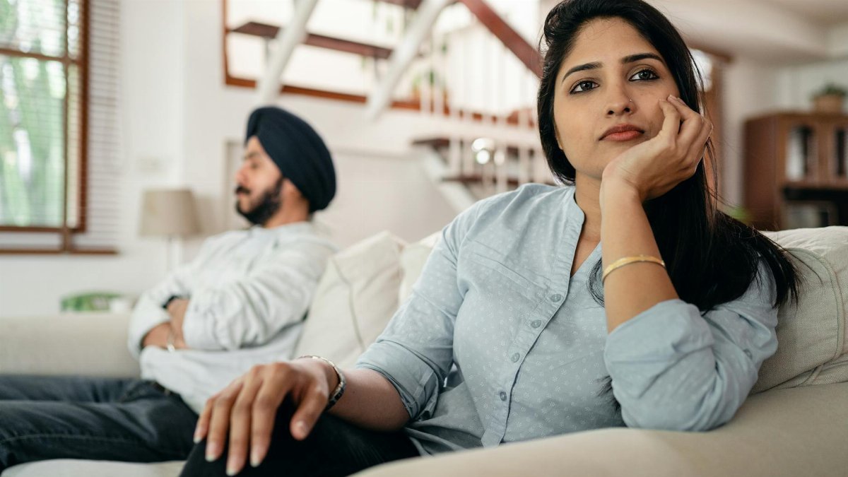 Young couple experiencing a conflict at home, showcasing emotional distance and contemplation.