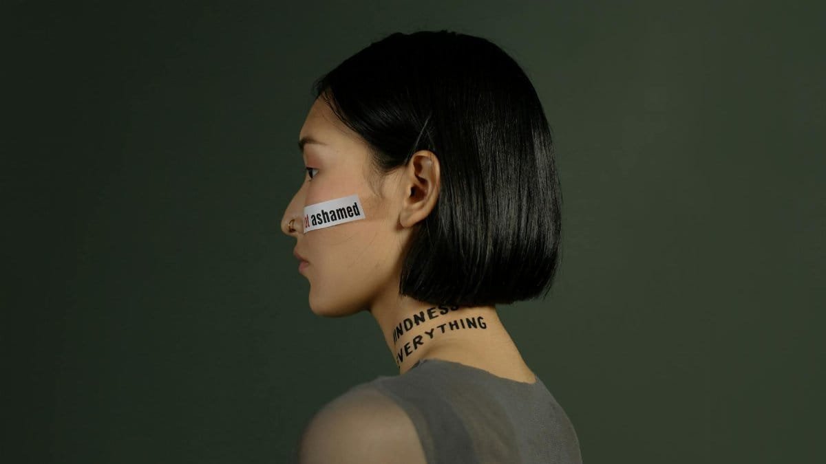 Side view of a young woman with words on her face and neck, symbolizing freedom and choice.