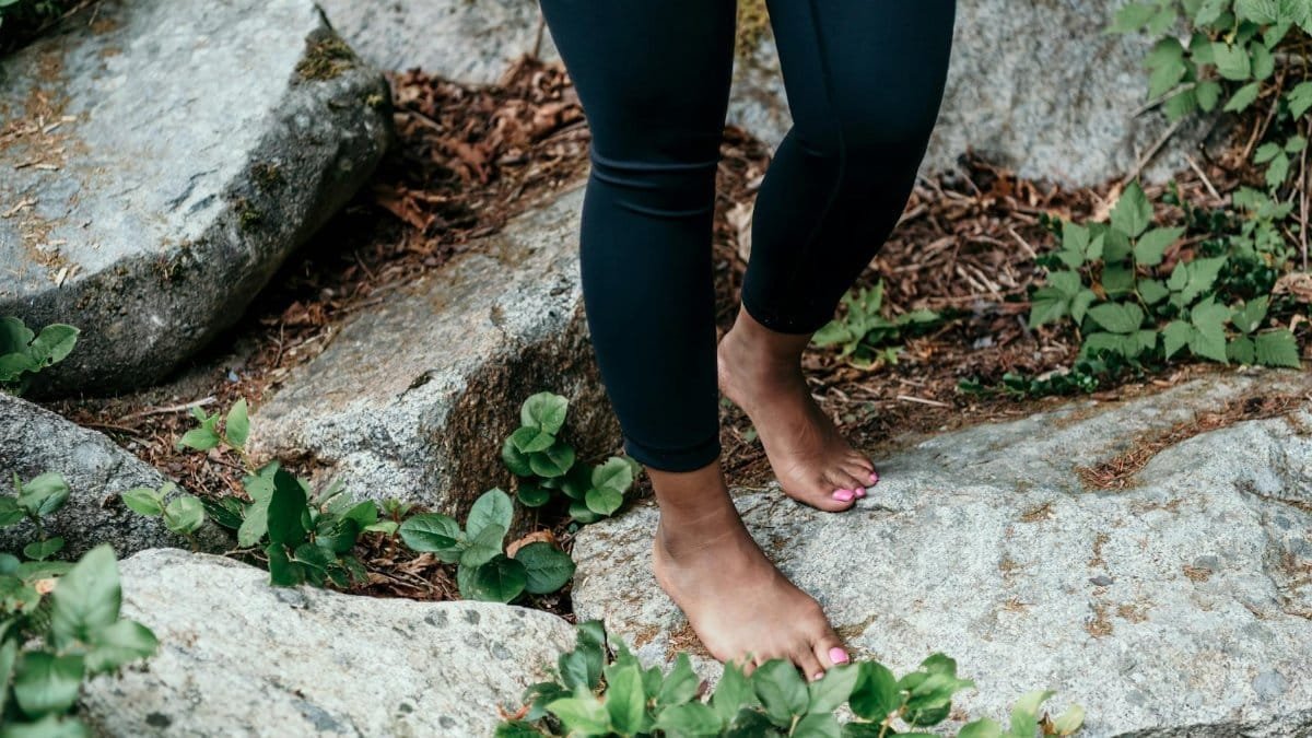 Person standing barefoot on natural rocks, connecting with nature, emphasizing grounding and mindfulness.
