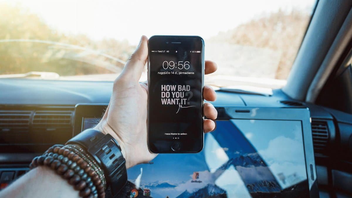 Close-up of a hand holding a smartphone in a car, highlighting technology and motivation.