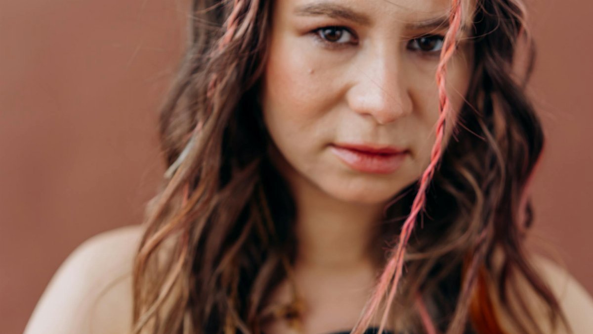 Close-up of a woman with braided hair meditating with a peaceful expression.