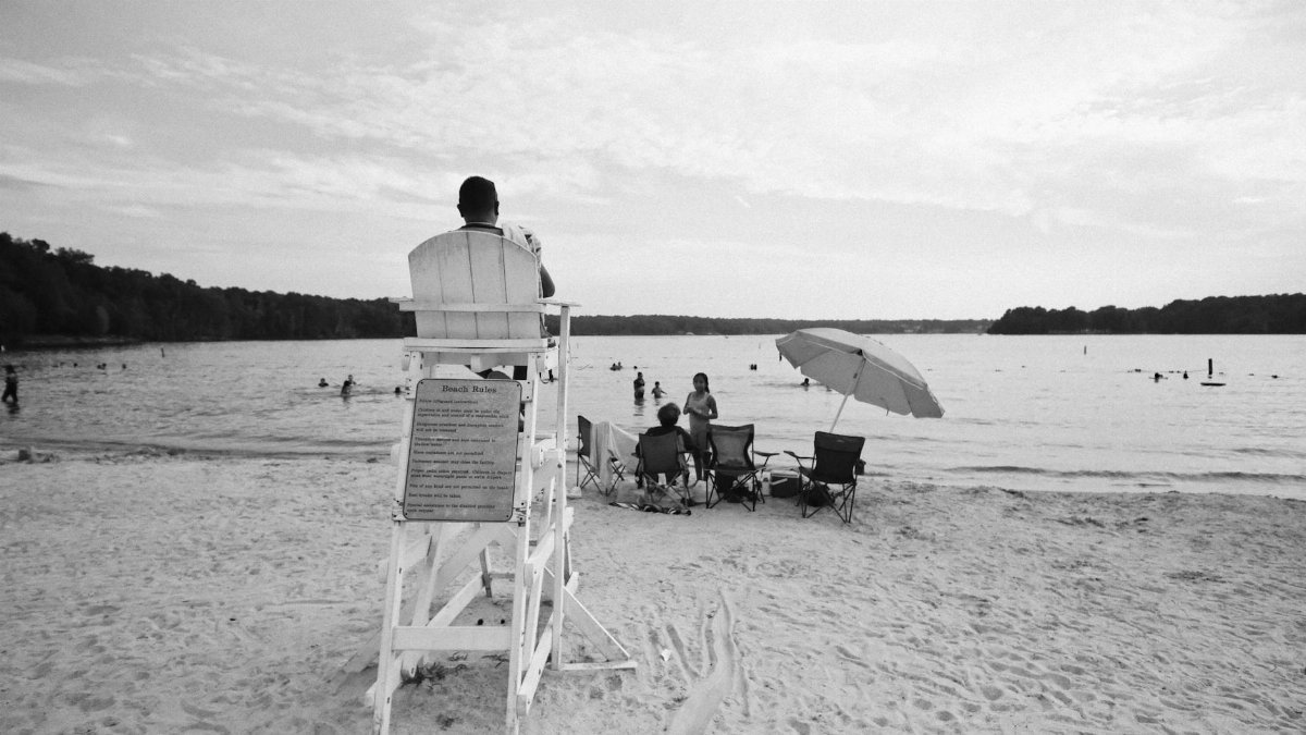 A serene black and white beach scene with people and lifeguard in Virginia.