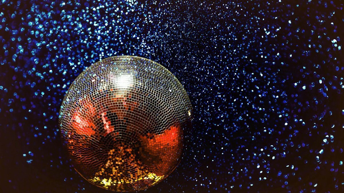Shining disco ball with colorful reflections in a dark, starry background.