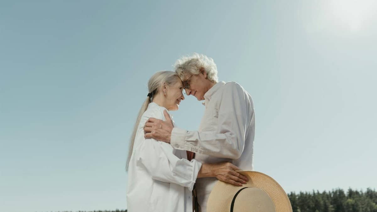 A senior couple shares a heartfelt embrace outdoors, symbolizing enduring love and connection.