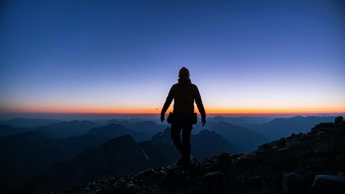 Silhouette of a hiker on a mountain peak during a stunning sunrise, capturing the essence of adventure.