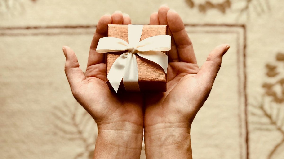 Close-up of hands holding a beautifully wrapped gift box with a ribbon, perfect for celebrations and surprises.