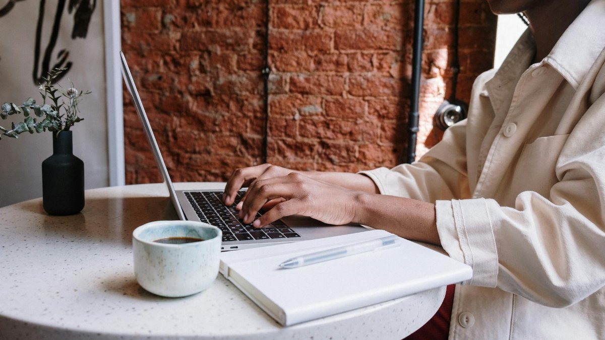 Woman working on a laptop with coffee in a cozy café, highlighting a productive and modern vibe.