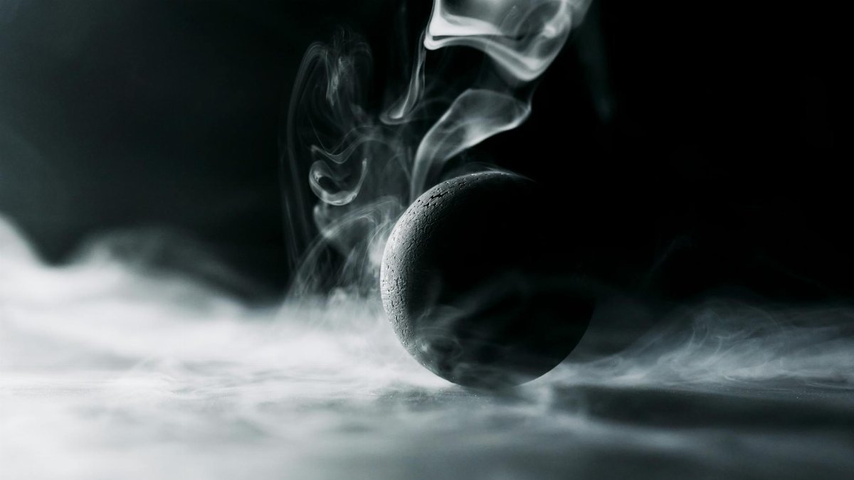 Abstract image of a black sphere engulfed in swirling, mysterious smoke.