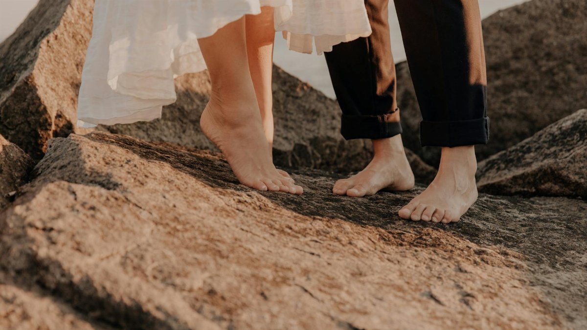 Barefoot couple standing on rocky terrain, depicting romance and connection.