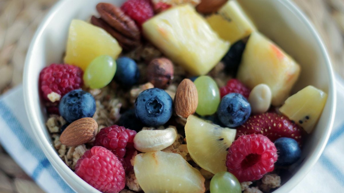 Close-up of a colorful muesli bowl with fresh berries, nuts, and pineapple.
