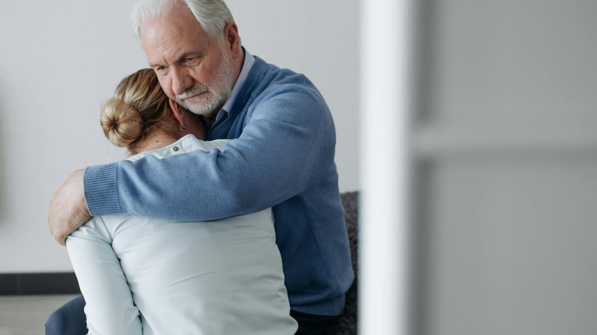 A senior man consoles a woman in a moment of grief, offering comfort and support.