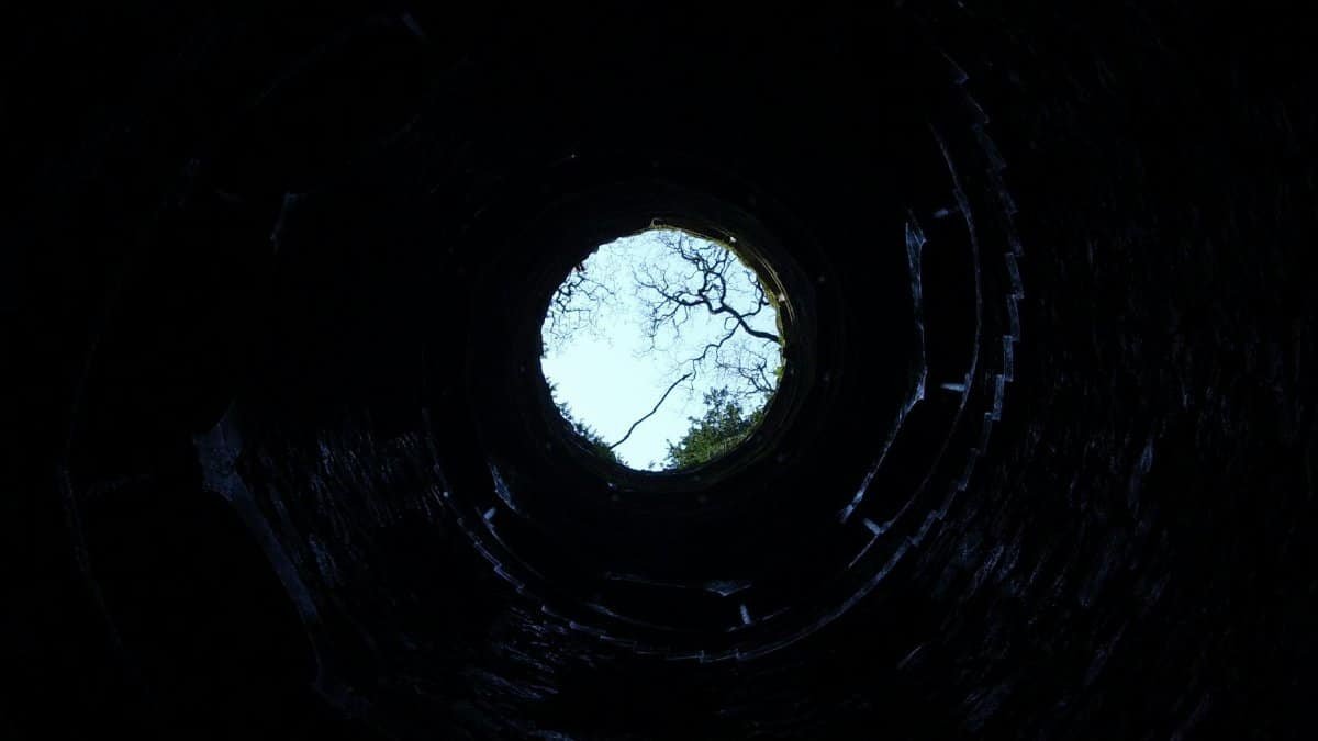 A dramatic upward view from inside a circular well in Sintra, Portugal.