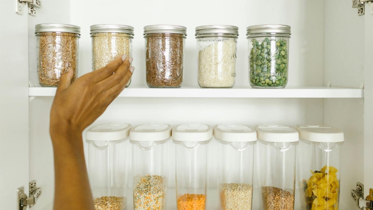 A neat pantry shelf showing various grains stored in labeled glass and plastic containers, promoting kitchen organization.