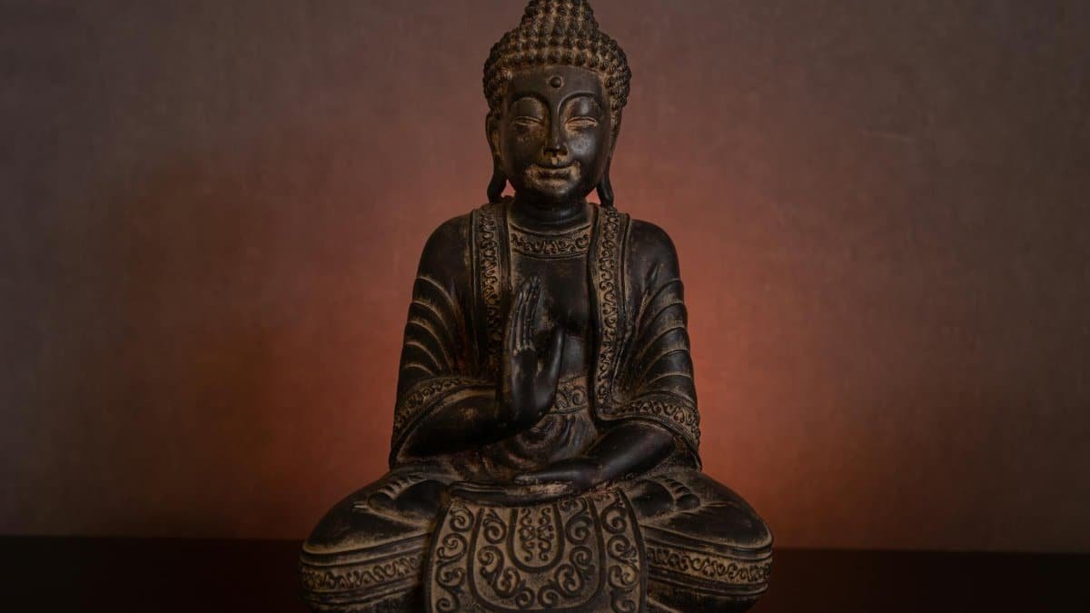 Bronze Buddha statue in Abhaya Mudra, glowing with spiritual calmness.