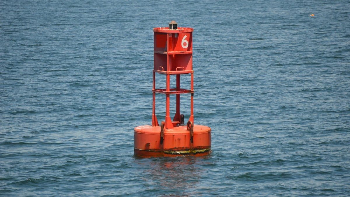 A red buoy marked with the number six floats in the blue waters of Boston Harbor.
