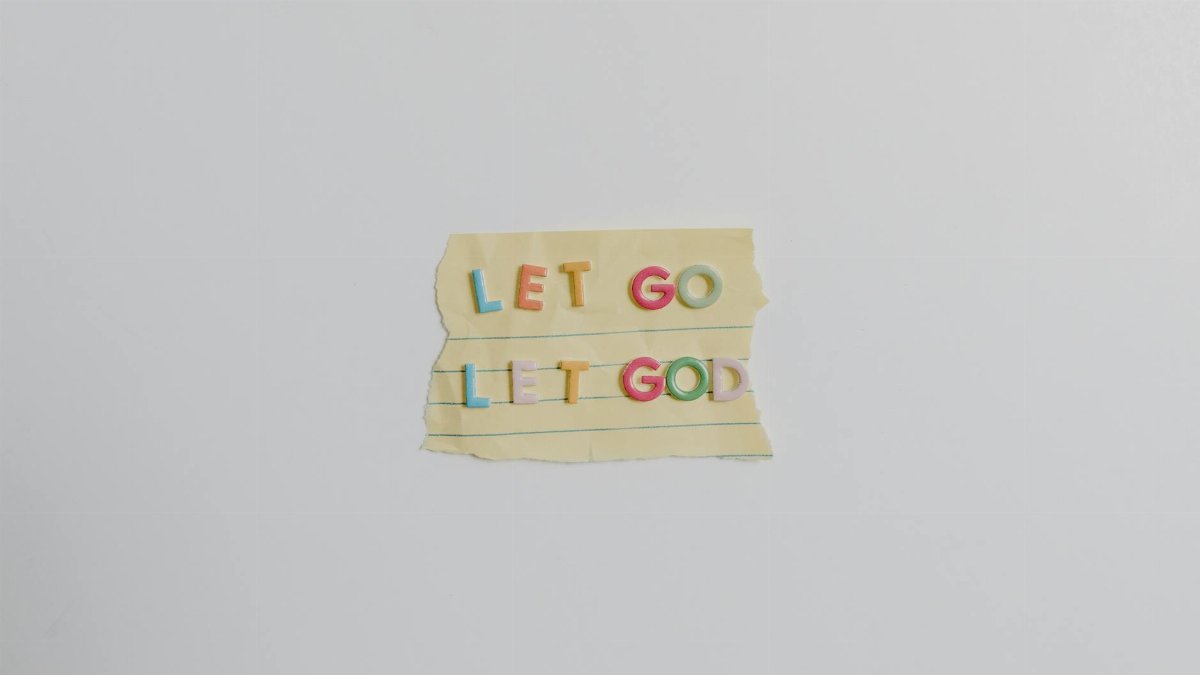 Minimalist image of a torn paper with the phrase 'Let Go, Let God' in colorful letters.
