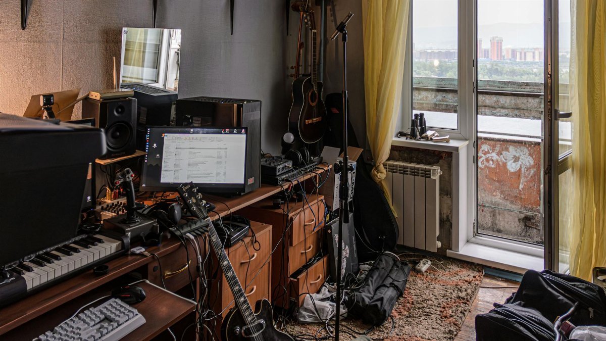 A cluttered home studio filled with musical instruments and sound equipment.