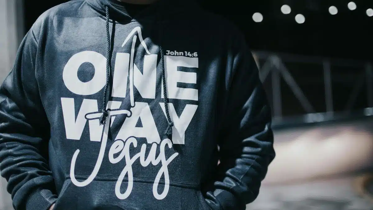 Close-up of a man in a hoodie with 'One Way Jesus' text on a dark street.