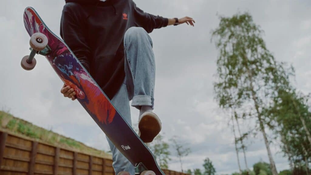 A young man executing a trick on a colorful skateboard in an outdoor setting.