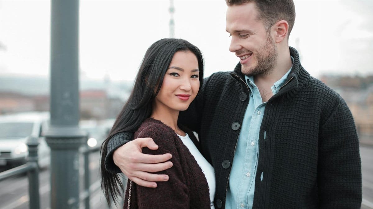 Affectionate couple enjoying a moment on a city bridge, expressing love and happiness.