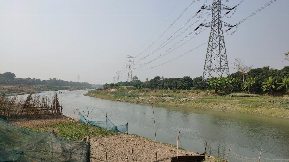 Power lines crossing a river in Chapai Nawabganj, capturing the blend of nature and technology.