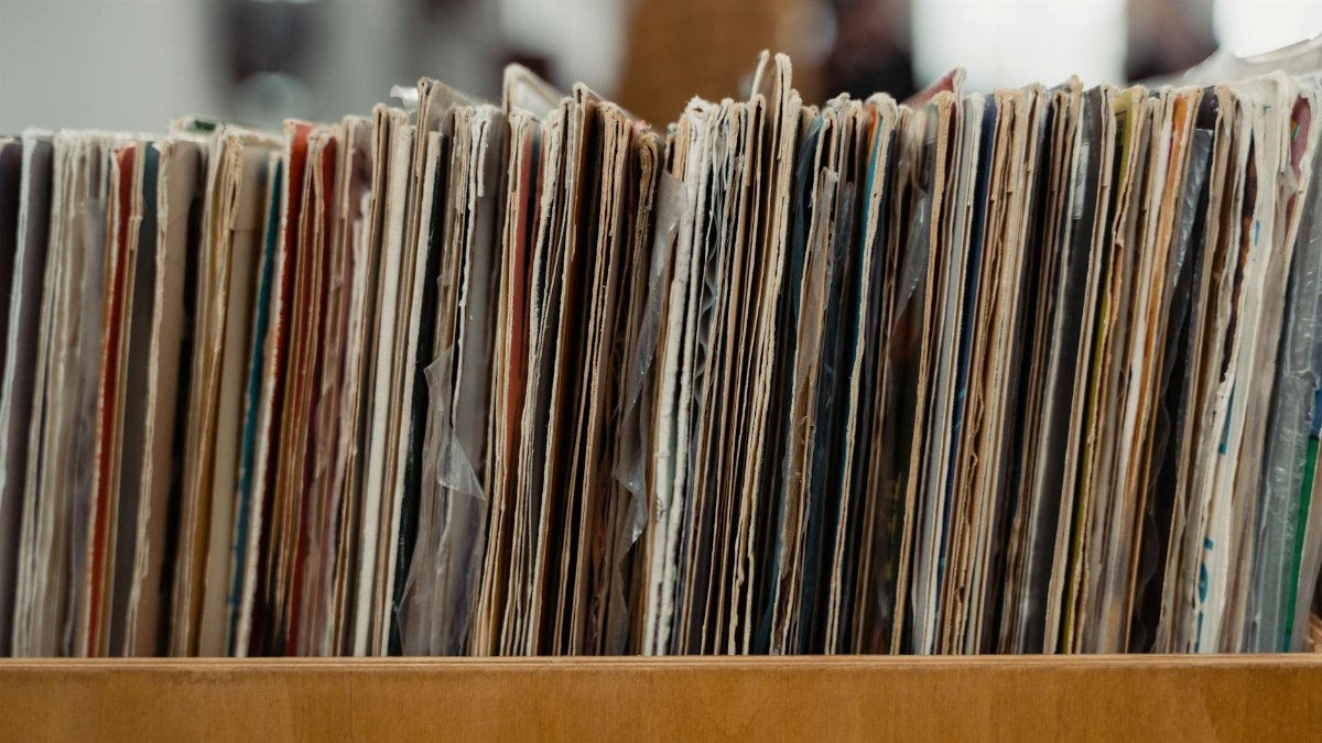 Stack of vintage vinyl records stored in a wooden crate, showcasing a retro vibe.