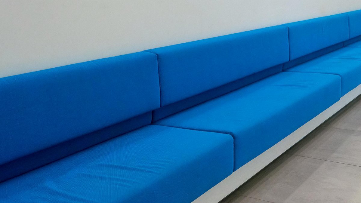 Long blue minimalist sofa seating against a white wall in a modern room.