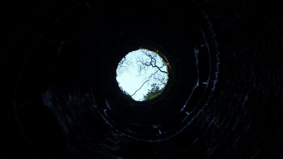 A dramatic upward view from inside a circular well in Sintra, Portugal.