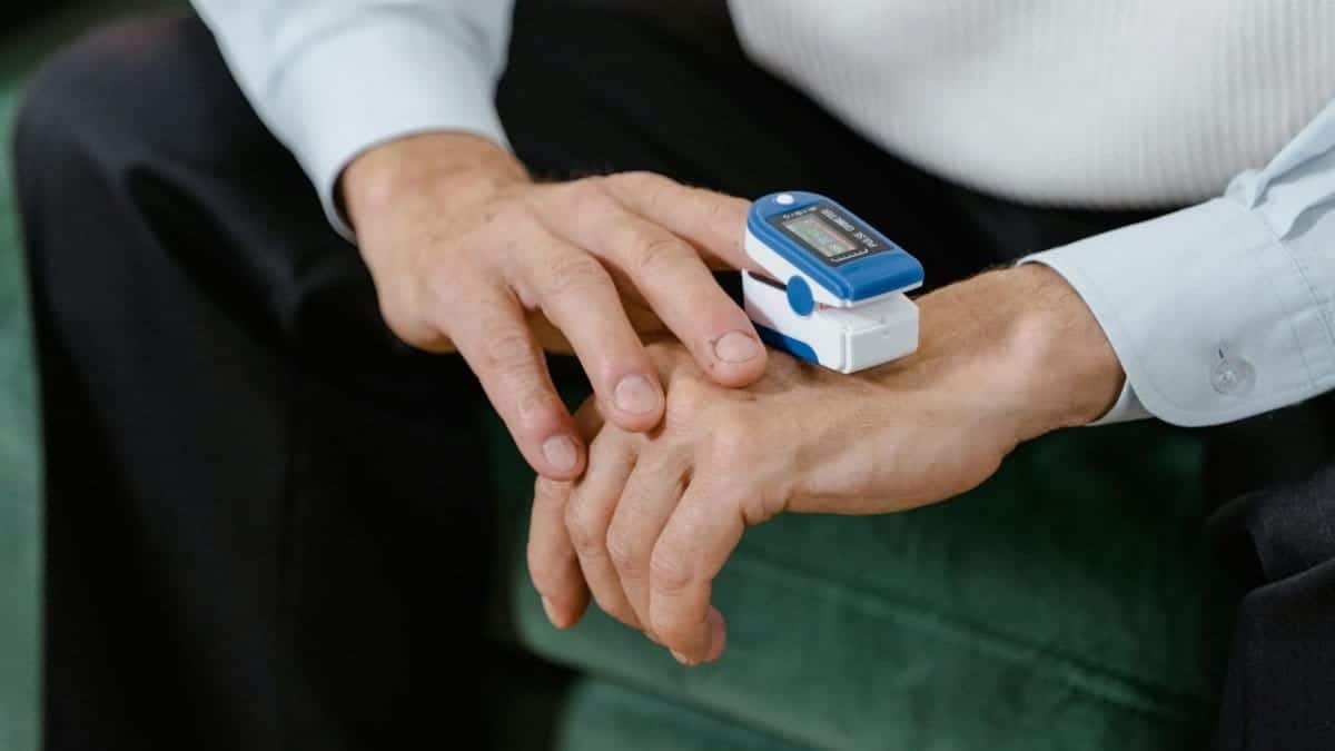 A pulse oximeter is monitoring blood oxygen levels on an adult's finger.