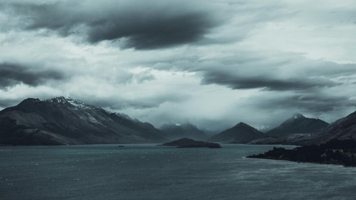 Mystical landscape with cloudy mountains over a serene lake, evoking a sense of calm and mystery.