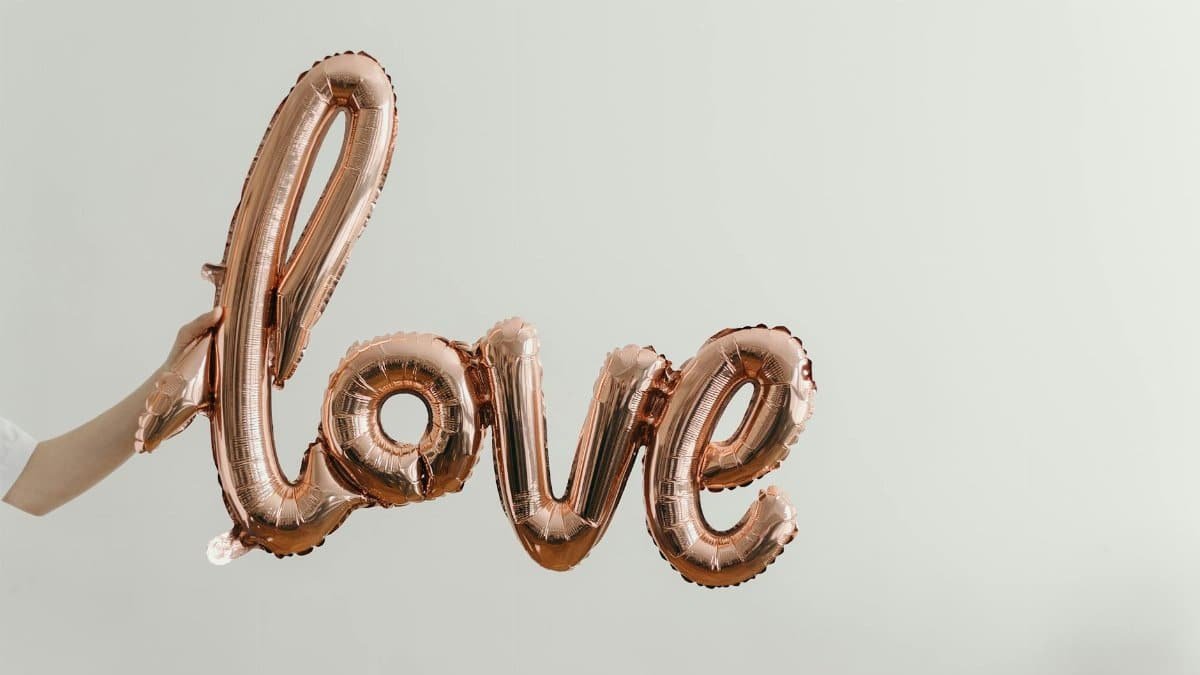 Elegant rose gold balloon spelling 'love' on a soft background, perfect for Valentine's Day themes.