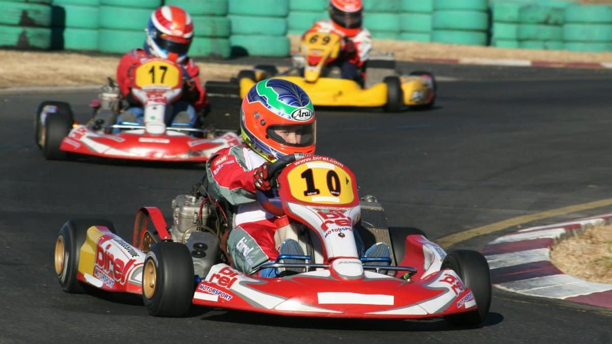 Three go-kart racers competing on a sunny outdoor track, showcasing speed and agility.