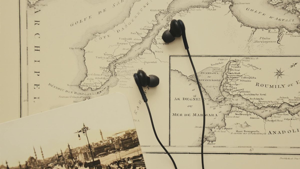 A vintage map with earphones and a historical photograph evoke a blend of history and modern technology.