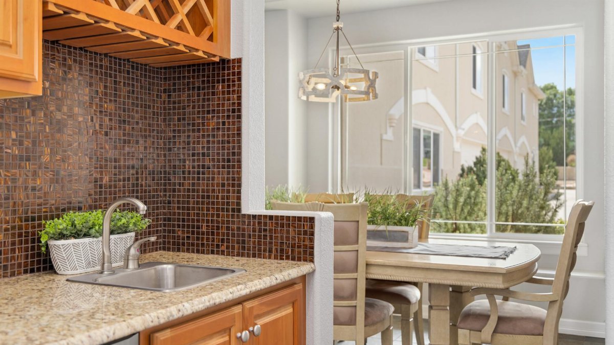 Contemporary kitchen and dining area with wooden cabinets and mosaic tile backsplash.