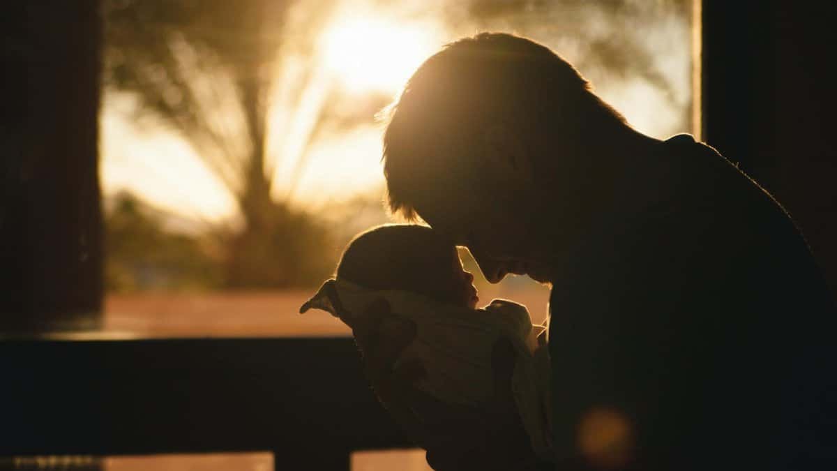 Silhouette of a father holding his newborn at sunset, highlighting love and connection.