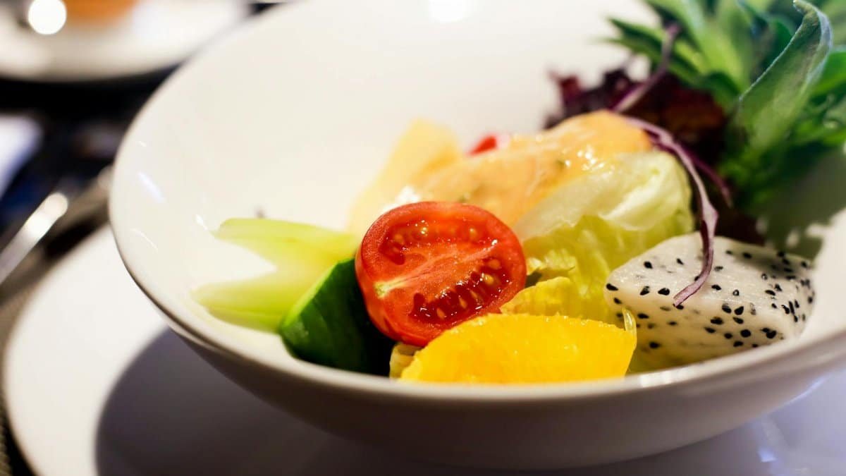 A fresh and colorful salad bowl featuring tomatoes, lettuce, cucumber, and dragon fruit, perfect for a healthy meal.